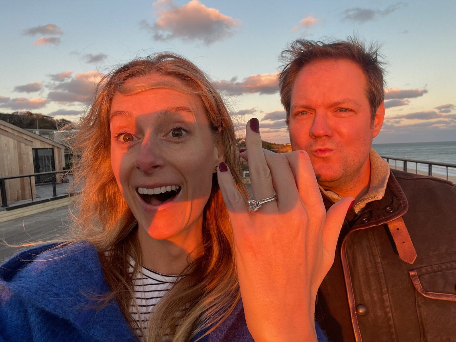 Phoebe and Chris celebrating their engagement at sunset by the beach
